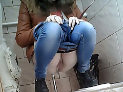 Slender girl in very taut blue jeans filmed in the toilet room