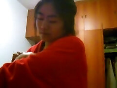 Fille asiatique avec des gros seins changements de vêtements dans sa chambre à coucher