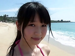 Slim Japanese gal Tsukasa Arai walks on a sandy beach under the sun