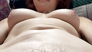 schrullige sexy lustige hippie-stiefmutter spielt mit ihren brüsten und ihrem bauch, während sie auf einem statischen fahrrad trainiert