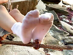 Goddess dasy phody in dirty white socks closeup against sea sunset