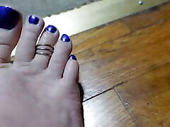 шевеление пальцами ног с кольцом на пальце и фиолетовыми ногтями на ногах