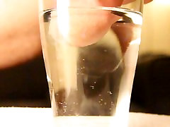 Close-up cumshot of circumcised cock in glass of water