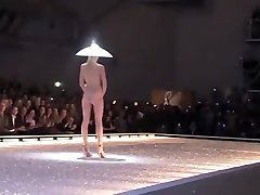 诱人的时装模特在一个奇怪的帽子走下讲台上裸体