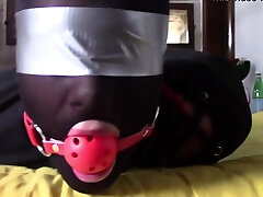 Slave girl lays on the floor wearing a ball-gag and high heels