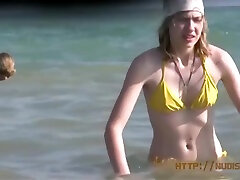 une belle adolescente au visage frais joue nue à la plage