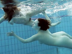 Two sexy babes chase each other while being naked in the pool