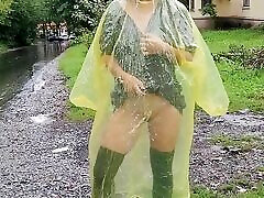 adolescente en impermeable amarillo muestra el girls school video sexy al aire libre bajo la lluvia