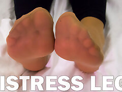Dominatrix soles in soft nylon socks is resting on the bed