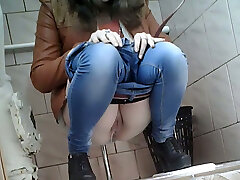 Slender girl in very taut blue jeans filmed in the toilet room